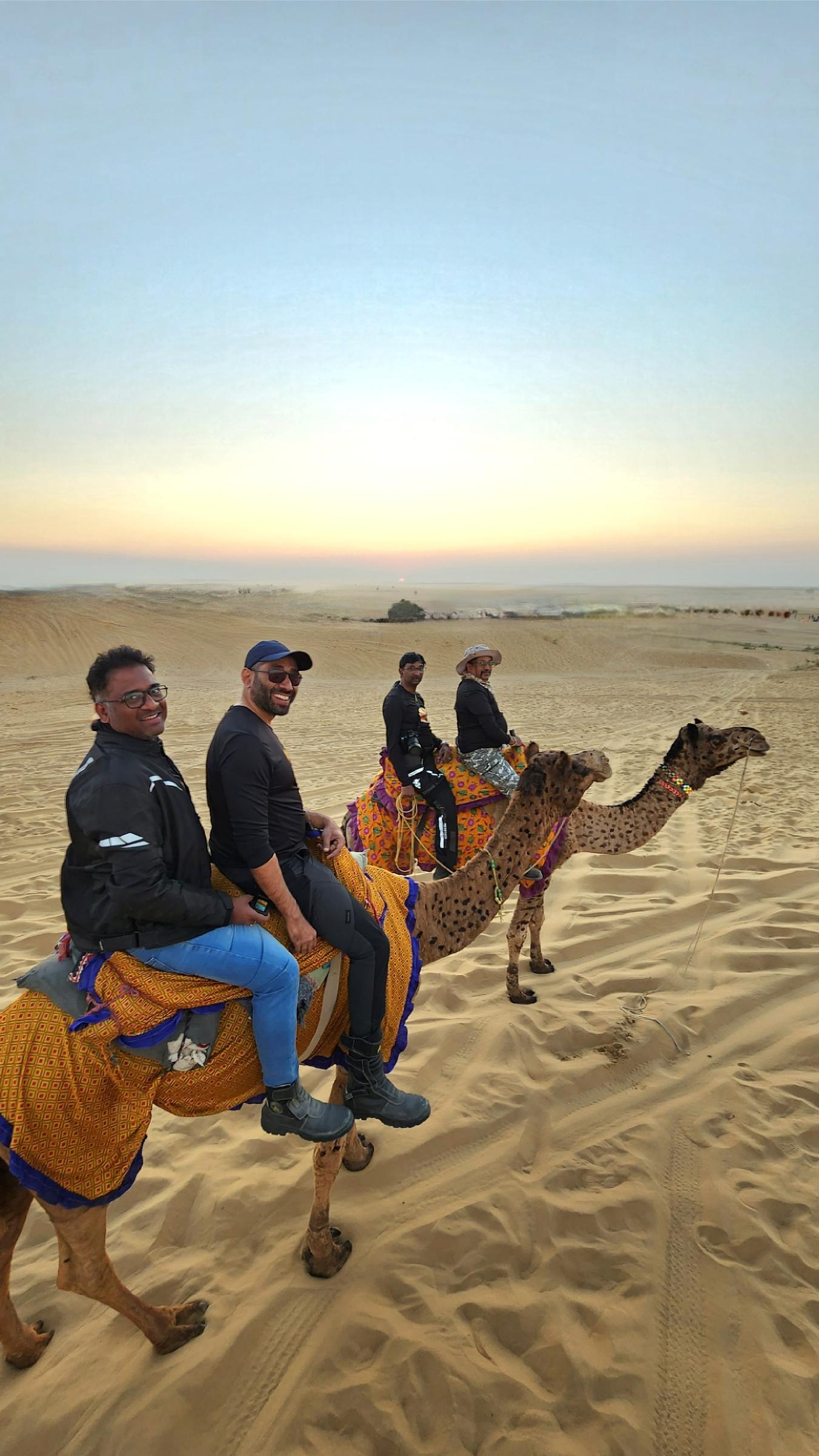 Riders on camels at sunset in Rajasthan.